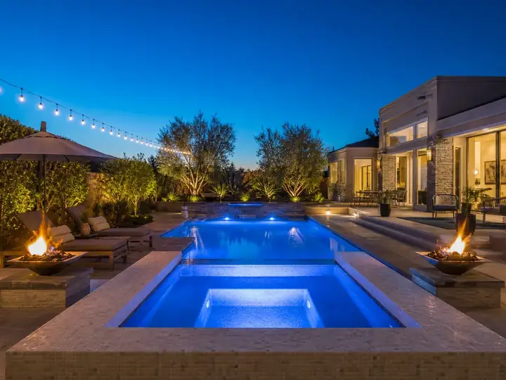 Pool and spa at dusk with LED lighting and fire bowls